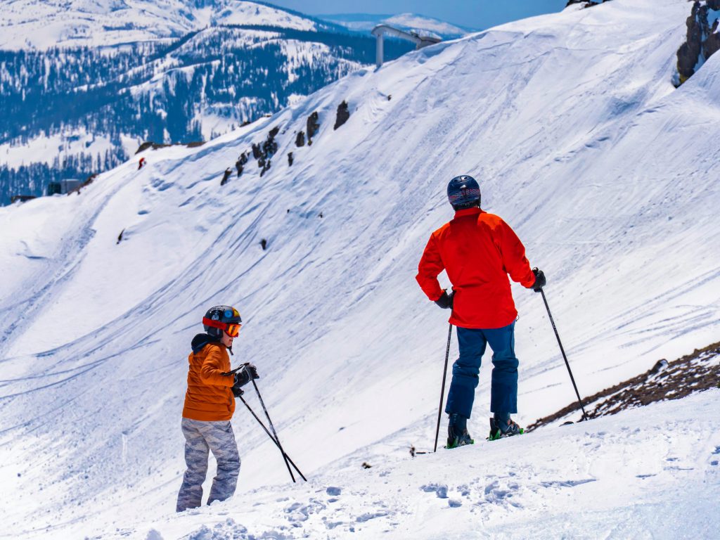 2 mensen op ski's in de sneeuw met oranje jassen