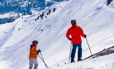 2 mensen op ski's in de sneeuw met oranje jassen